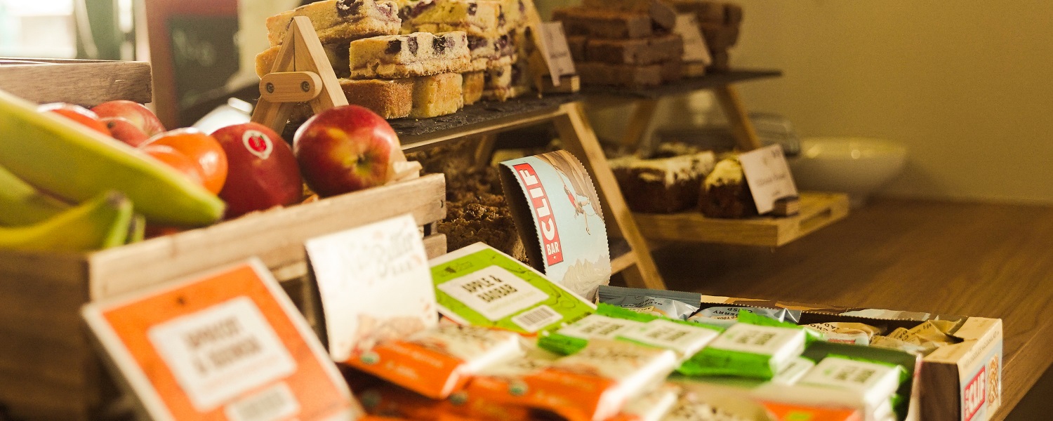 A display of food including fruit, healthy snack bars and cakes