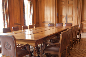 a wood panelled room with a large wooden table and leather armchairs