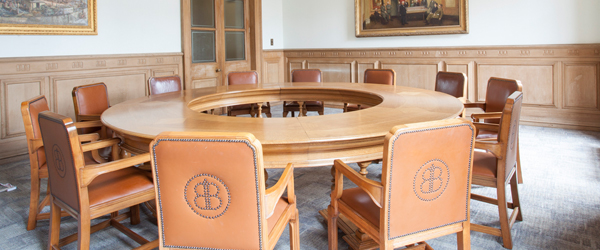 a half panelled room with a round wooden table and leather chairs