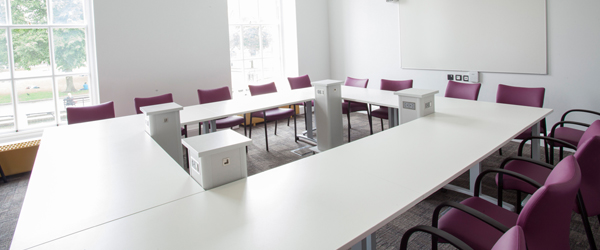 a large bright meeting room with a square white table and red chairs