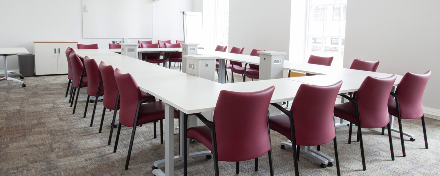 a large bright meeting room with a square white table and red chairs