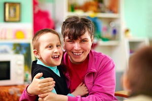 A teacher hugging a toddler in a classroom