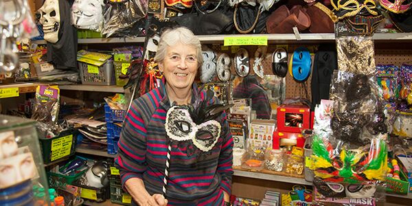 Lady holding a mask in front of some toys