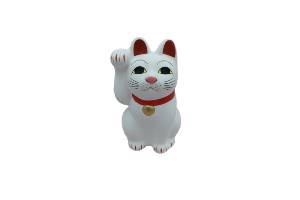 A white ornamental cat waving its paw