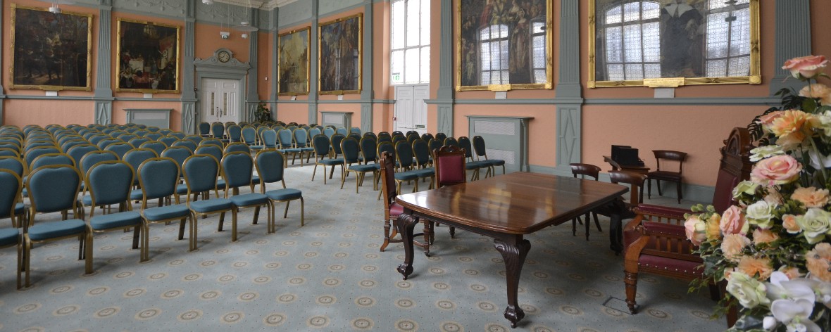 a room with rows of chairs and paintings on every wall